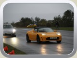 Gelber Tesla vor einem silbernen Porsche.
